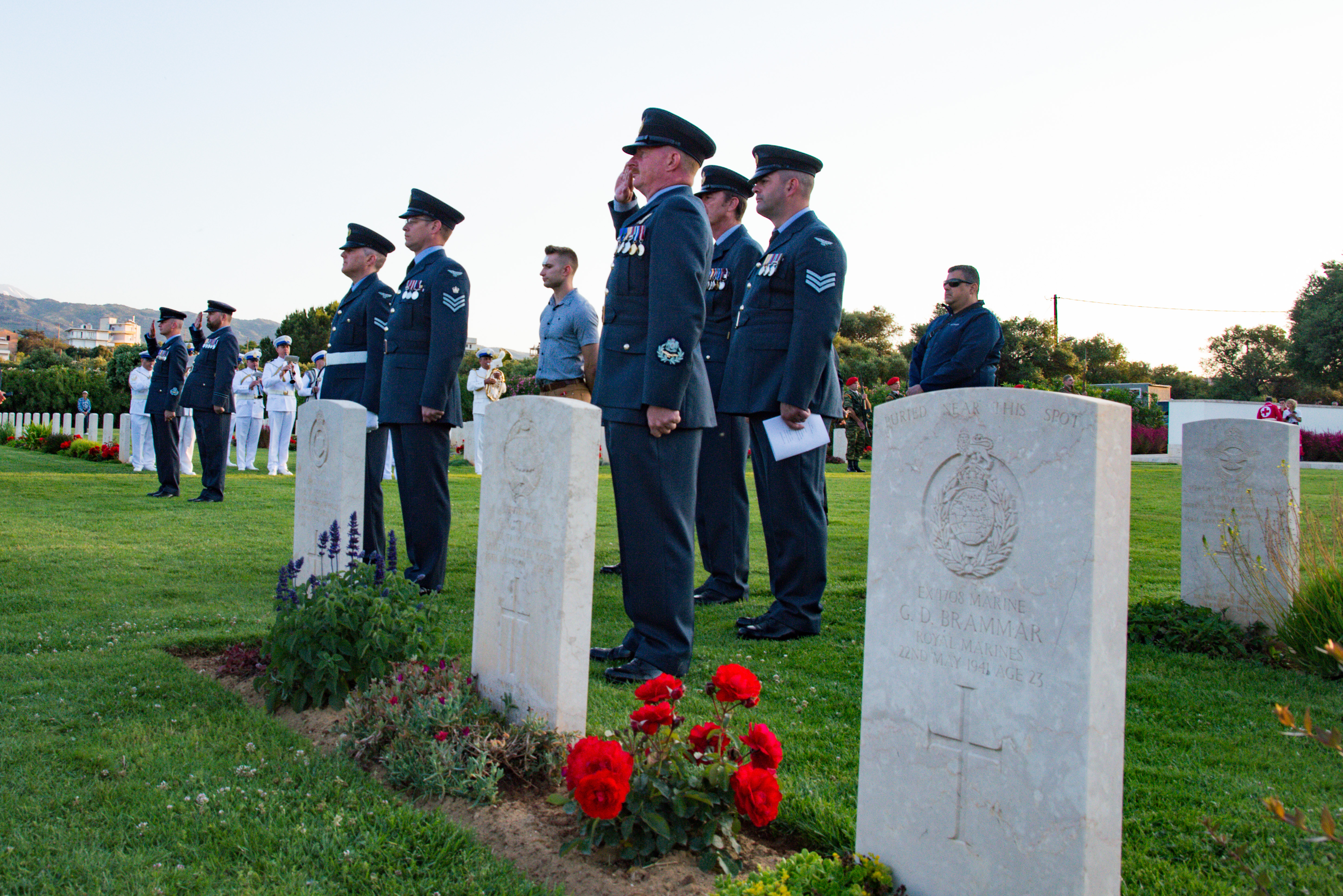 Personnel salute by memorial graves.